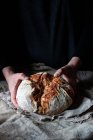 Невизначена людина кладе хліб на лляну тканину на стіл на чорному тлі — стокове фото