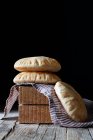 Fresh pita flatbread placed on napkin and wooden blocks on rustic table against black background — Stock Photo