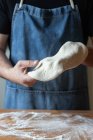 Macho irreconhecível no avental achatamento massa macia sobre a mesa com farinha enquanto cozinha pizza — Fotografia de Stock