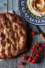 From above loaf of Ramazan pidesi placed near fresh tomatoes and spices on lumber tabletop — Stock Photo