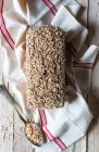 Du dessus du pain de ryecorn savoureux placé sur une serviette en tissu près d'une cuillère de grain sur un fond en bois — Photo de stock
