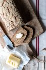 From above loaf of tasty ryecorn bread placed on cloth napkin near spoon of grain on wooden background — Stock Photo