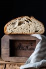 Pane fresco dimezzato con semi contro parete di legno — Foto stock