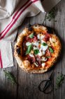 Draufsicht auf köstliche frische Sommerpizza auf Holztisch in der Nähe von Handtuch und Schere in rustikaler Küche — Stockfoto