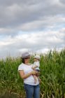 Entzückende Mutter und Kind auf der Hand genießen und lachen auf dem Feld — Stockfoto