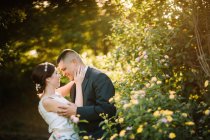 Seitenansicht eines anmutigen, zarten Hochzeitspaares, das sich verbindet und im Garten in die Augen schaut — Stockfoto