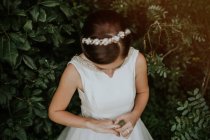 Наречена в діадемі і елегантна сукня, насолоджуючись кільцем на пальці в зеленому саду — стокове фото