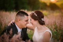Sorrindo noivo e noiva abraçando e beijando no parque — Fotografia de Stock