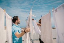 Homens multirraciais pendurando roupas em dia brilhante — Fotografia de Stock
