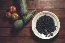 Reife Brombeeren garniert mit Gemüse in Schüssel auf Holzgrund — Stockfoto