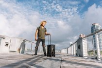 Traveler man with a hat walking with suitcase in the street — Stock Photo