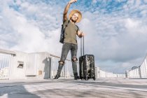 Портрет хипстера в полный рост, делающего селфи с чемоданом на улицах города — стоковое фото