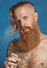 Pensivo confiante adulto de cabelos vermelhos hipster acendendo cigarro e olhando para a câmera — Fotografia de Stock