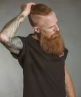 Confiante adulto de cabelos vermelhos hipster tocando o cabelo e olhando para longe — Fotografia de Stock