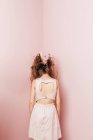 Vista conceitual por trás de uma adolescente com cabelos emaranhados no fundo rosa — Fotografia de Stock