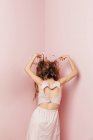 Konzeptueller Blick von hinten auf ein Teenager-Mädchen mit wirren Haaren auf rosa Hintergrund — Stockfoto