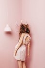 Vista conceptual desde atrás de una adolescente con pelos enredados sobre fondo rosa - foto de stock
