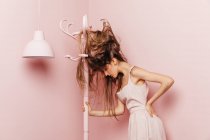 Vue de face d'une adolescente aux cheveux enchevêtrés sur fond rose — Photo de stock