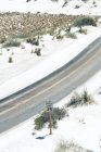 Von oben Landstraße auf staubigem Feld mit Hochspannungsleitung und abgelegener Gebirgskette im White Sands National Monument, New Mexico, USA — Stockfoto