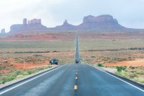 Rural highway at dusty field with power line and remote mountain range in Forrest Gump Point, USA — Stock Photo