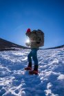 Persona irriconoscibile con zaino e attrezzatura da trekking contemplare mentre si cammina in un pendio alla luce del giorno — Foto stock