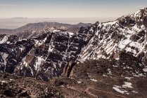 Ruhige felsige Hänge der Bergkette mit schneebedeckten Gipfeln bei Tageslicht — Stockfoto