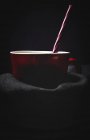 Tasse weiße Milch mit hell gestreiftem Stroh auf Tisch vor schwarzem Hintergrund — Stockfoto