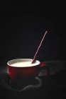 Cup of white milk with bright striped straw on table over black background — Stock Photo