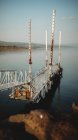 Старий іржавий пірс з далеким туристом, розташований біля спокійної морської води під час сутінків — стокове фото
