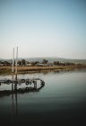 Antiguo muelle oxidado con turista distante situado cerca de agua de mar pacífica durante el atardecer - foto de stock