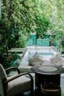 Banc souple avec oreillers situé près de la piscine propre dans le jardin verdoyant de l'hôtel à Marrakech, Maroc — Photo de stock