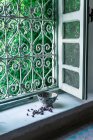 Piccoli boccioli di fiori secchi e ciotola ornamentale collocati vicino alla finestra aperta all'interno della tradizionale casa araba a Marrakech, Marocco — Foto stock