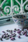 Pequenos botões de flores secas e tigela ornamental colocados perto da janela aberta dentro da casa árabe tradicional em Marraquexe, Marrocos — Fotografia de Stock