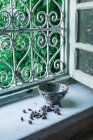 Pequenos botões de flores secas e tigela ornamental colocados perto da janela aberta dentro da casa árabe tradicional em Marraquexe, Marrocos — Fotografia de Stock