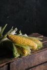 Аранжування свіжих збираних кукурудзяних качанів на дерев'яній ящику — стокове фото
