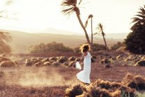 Side view of woman in white dress walking in field with dry grass in Fuerteventura, Las Palmas, Spain — Stock Photo