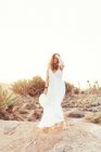 Woman in white dress in dry field in sunlight — Stock Photo