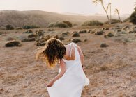 Femme en robe blanche dans un champ sec au soleil — Photo de stock