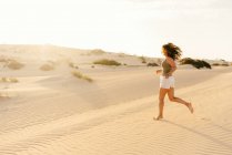 Active woman running in dry desert barefoot — Stock Photo