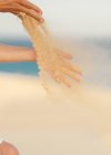 Женщина выпускает песок в руках на ветру — стоковое фото