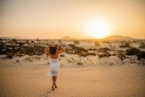 Mulher ativa em vestido branco andando no deserto seco descalço — Fotografia de Stock