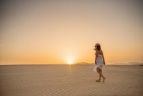 Активна жінка в білому одязі, яка ходить у сухій пустелі босоніж. — стокове фото