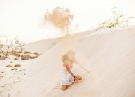 Mujer divirtiéndose arrojando arena en el desierto - foto de stock