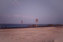 Route vide avec panneaux ronds sur des piliers en bois le long de l'océan à Fuerteventura, Las Palmas, Espagne — Photo de stock