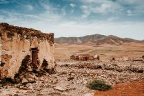 Захватывающий дух пейзаж старых заброшенных кирпичных домов в сухой пустыне в окружении гор в Фуэртевентуре, Лас-Пальмас, Испания — стоковое фото