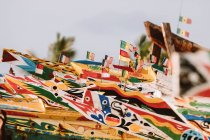 Barcos pesqueros de madera con frentes coloridos y varias banderas pequeñas ubicadas en el puerto de la ciudad en Gambia - foto de stock