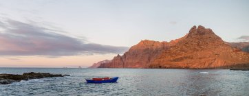 Голубой парусник в море и красивые скалы — стоковое фото