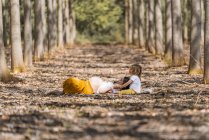 Беременная мать и маленькая дочь отдыхают на земле в парке — стоковое фото