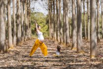 Весела вагітна мати і дочка практикують йогу в парку під час сонячної погоди — стокове фото