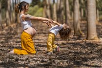 Mãe grávida e pequena filha de mãos dadas no parque — Fotografia de Stock